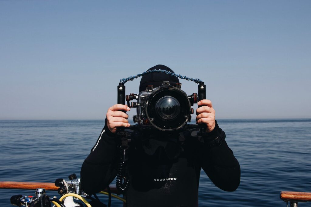 Diver holding underwater camera housing at the surface